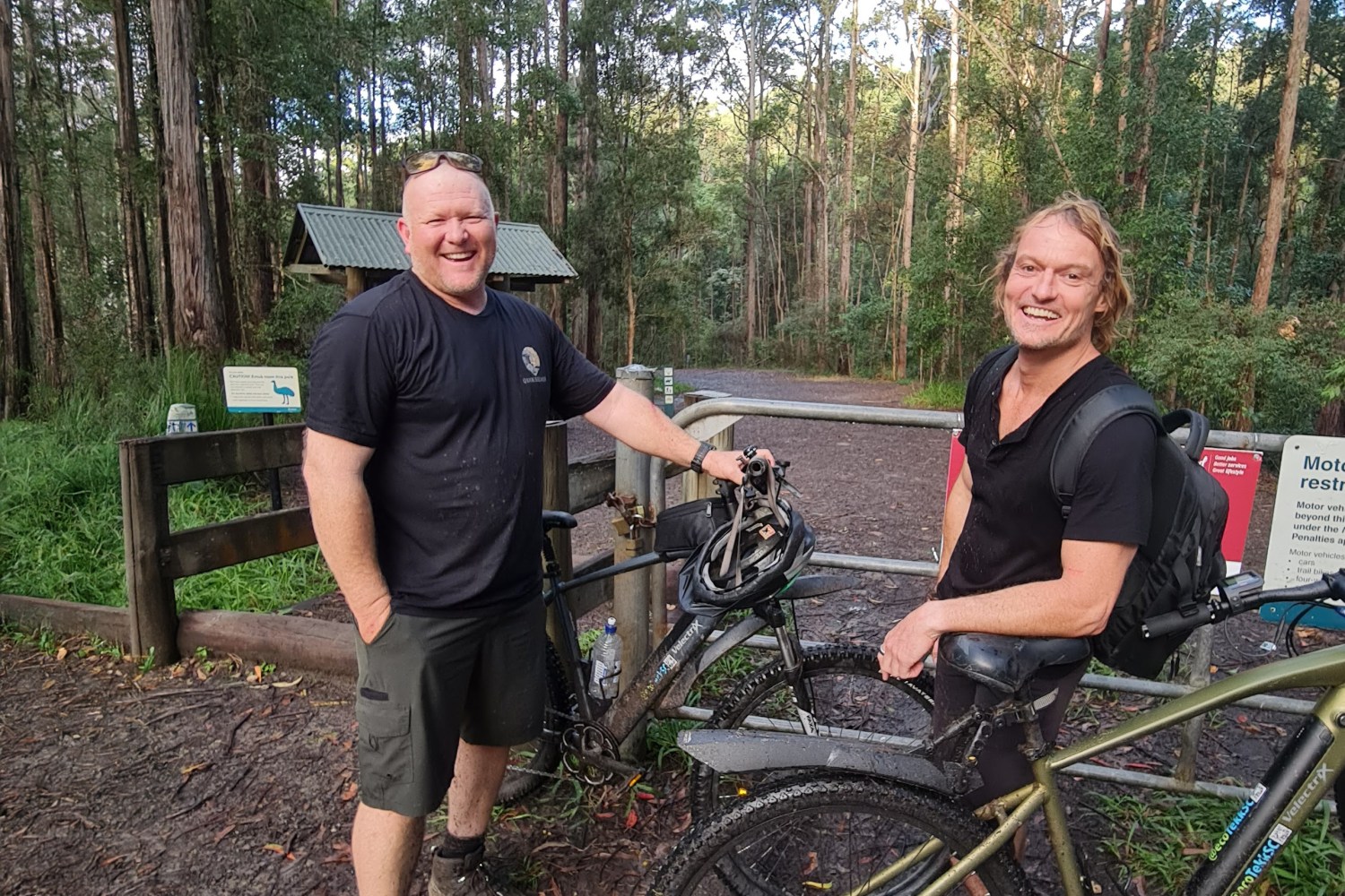 Oliver and James smiling with their muddy e-bikes at Parklands MTB Trail.